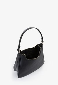 Borsa a mano in pelle nera con forma curvata, chiusura con zip e manico testurizzato. L'interno è semplice e presenta un rivestimento morbido.