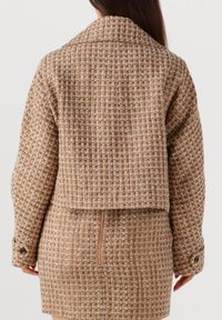 Bruine getextureerde tweed jasje en rok set, met een cropped ontwerp, kraag en knoopmanchetten met een ritssluiting op de rok.