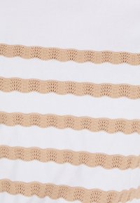 Witte stof met horizontale beige scalloped borduursels, met ingewikkelde waaiervormige patronen, die een contrast in textuur creëren.