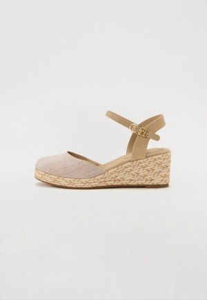 Beige espadrille kile sandal med en tekstureret stofoverdel og justerbar ankelrem; jute-vævet mellemsål, flad gummisål.