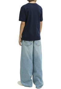 Camiseta de algodón azul marino de mangas cortas combinada con jeans de denim anchos de un azul claro. El conjunto presenta un ajuste relajado.