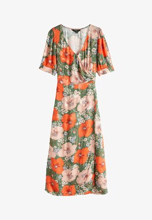 Sukienka w kwiaty z dużymi pomarańczowymi i różowymi kwiatami na zielonym tle, z krótkimi rękawami i średniej długości dołem. Białe sandały na płaskiej podeszwie.