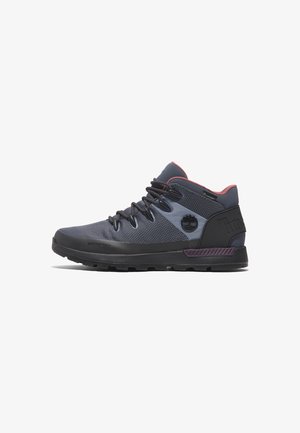 Chaussures de randonnée étanches mi-hautes avec une tige en maille gris foncé, des accents violets et une semelle noire robuste aux crampons prononcés.