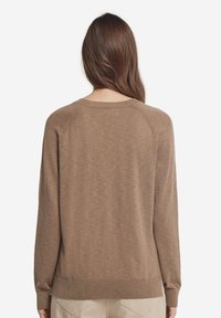 Brun långärmad tröja med en mjuk textur, ribbad nederkant och raglansärmar, med en enkel, neutral design.