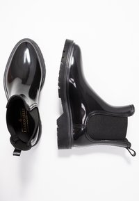 Botas de lluvia negras brillantes con paneles laterales elásticos, suelas de goma texturizada y tiradores. Acabado liso, punta redonda y diseño duradero.