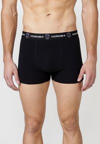 Fekete boxer alsónadrág rugalmas anyagból, testhezálló kialakítással. Fekete derekú, szürke logóval és koponya mintával.