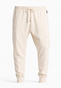 Pantalones jogger de tejido de waffle color beige con cintura elástica, cordón frontal, costuras laterales y puños acanalados.