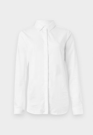 Chemise blanche à manches longues en coton lisse. Présente un col classique et un devant à boutons avec un ourlet droit et sans motifs.