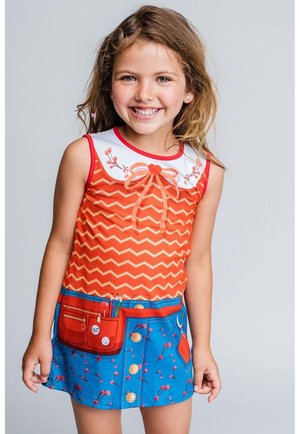 Pomarańczowy top na ramiączka w zygzakowaty wzór z białym kołnierzykiem, czerwonym kokardą i kwiatowymi detalami; niebieska spódnica z kieszenią i guzikami, ozdobiona kwiatowym wzorem.