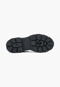 Zwarte rubberen zool met een robuust loopvlak; heeft dikke groeven voor grip en een ronde neus voor stabiliteit.