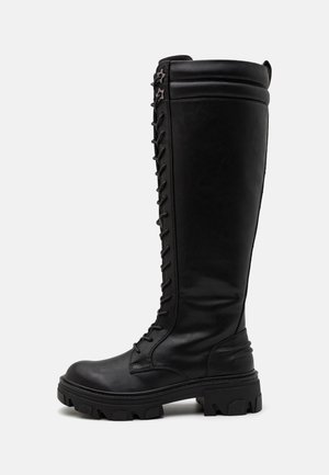 Schwarze knöchelhohe Stiefel aus glattem Leder. Sie verfügen über eine Schnürung vorne, sternförmige Akzente an der Seite und eine robuste, strukturierte Sohle.