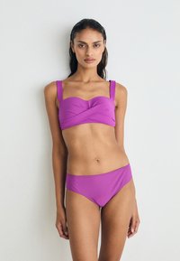 Lila bandeau bikini felsőrész széles pántokkal és csavart elemmel, párosítva hozzá illő csípőnadrággal, sima anyagból készült.