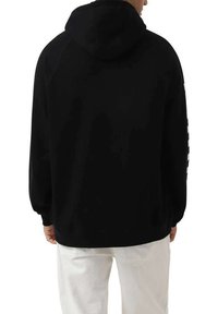 Sudadera negra ajustada, con una capucha grande y textura suave. Presenta rayas blancas a lo largo de la manga izquierda y puños acanalados.