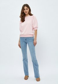 Ljusrosa sweatshirt med puffärmar, ribbad mudd och nederkant. Också en kombination med ljusblå utsvängda jeans och bruna klacksandaler.