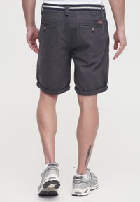Gray linen shorts with rolled cuffs, featuring back pockets and a striped waistband. Worn with gray athletic shoes.