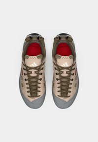 Παπούτσια αναρρίχησης σε μαυρισμένο χρώμα με γκρι λαστιχένιες σόλες, εξοπλισμένα με κορδόνια σε ελιά πράσινο, υφή στην κορυφή και κόκκινη εσωτερική σόλα με λεπτομέρεια σήματος.