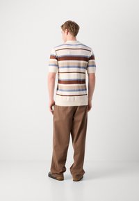 Kortermet stripete polo-skjorte i krem, blå, brun og beige farger; teksturert strikket stoff med ribbet krage og kant.