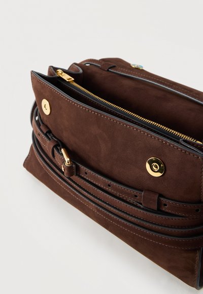 Bruine suède schoudertas met gouden magnetische drukknoopsluiting, verstelbare riem en centrale ritsvak.