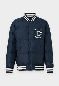 Námornícka páperová bunda s bielym logom 'C', zapínaním na cvoky, rebrovanými pruhovanými manžetami a golierom, a hladkou, lesklou textúrou.