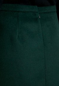Groene wollen rok met een gladde textuur, met een eenvoudig ontwerp, rechte snit en een discreet ritsdetail bij de taille.