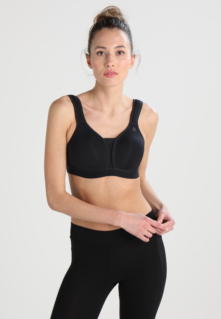 Soutien-gorge de sport noir avec larges bretelles, bonnets moulés et texture lisse. Associé à des leggings noirs taille haute, mettant en valeur une coupe ajustée.