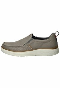 Zapato tipo slip-on en gris claro, con parte superior de malla, suela flexible y detalles texturizados. Los acentos marrones cerca del talón añaden contraste.