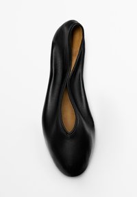 Scarpa piatta in pelle nera con design allungato e spaccato, texture liscia e interno color marrone chiaro. Forma minimalista senza elementi metallici visibili.