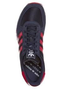 Tummansininen urheilujalkine punaisilla yksityiskohdilla, tekstiilistä valmistettu päällinen, nauhakiinnitys ja merkkisisäpohja. Sivuilla kolme punaista raitaa.