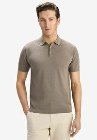Beige kortärmad polo med en strukturerad mönstring, treknappslås och ribbad krage och ärmslut, i kombination med ljusa byxor.