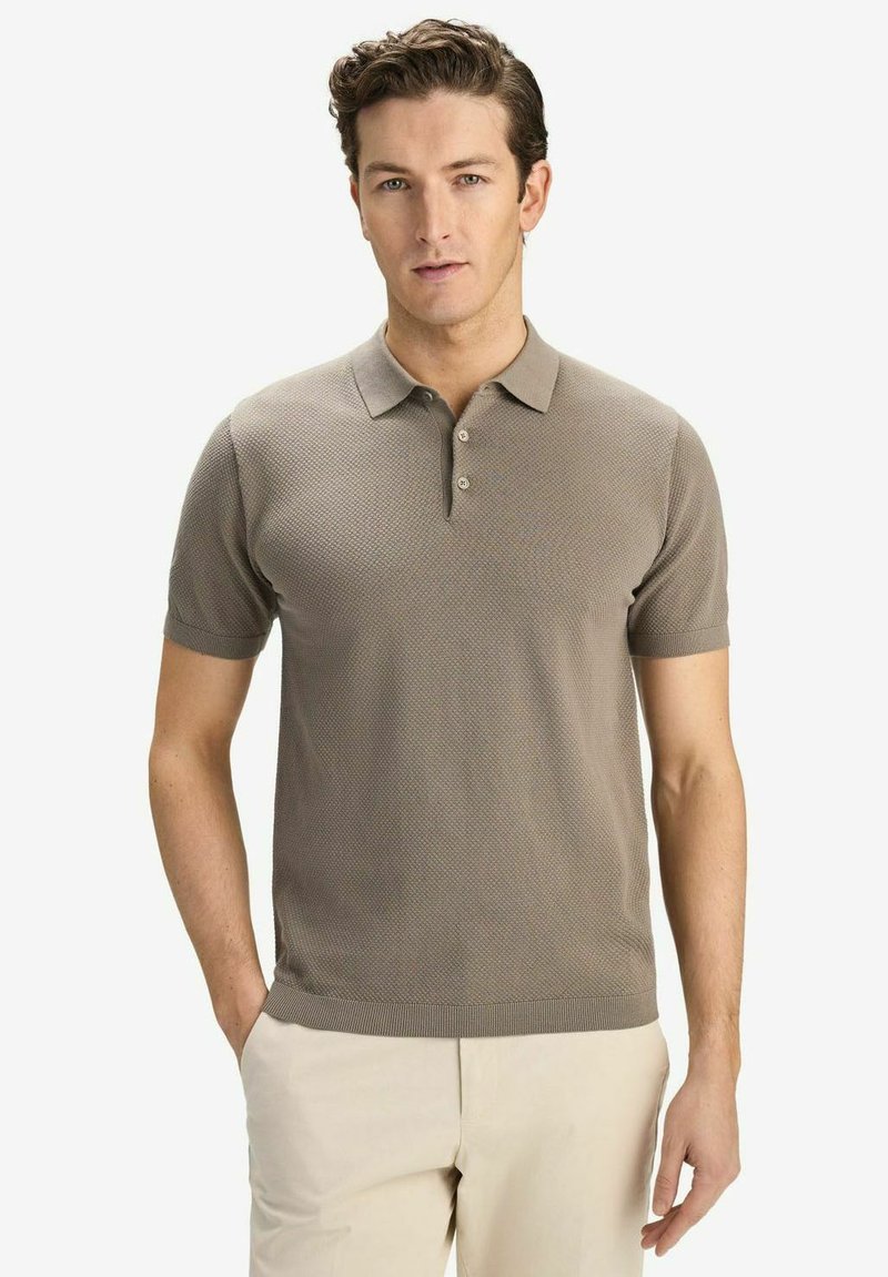Beige kortärmad polo med en strukturerad mönstring, treknappslås och ribbad krage och ärmslut, i kombination med ljusa byxor.