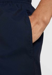 Granatowe szorty wykonane z lekkiego materiału, z elastycznym pasem i boczną kieszenią. Gładka tekstura z subtelnym połyskiem.