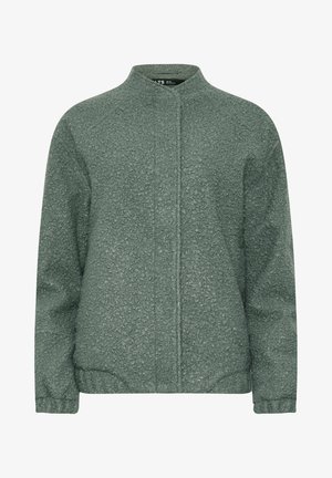 Zielona kurtka o fakturze z kołnierzem typu stójka, z zamkiem błyskawicznym z przodu i elastycznymi mankietami. Materiał ma wzór przypominający małe kropki.