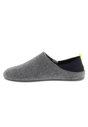 Zapato gris tipo slip-on con un talón de tela negra y una pequeña pestaña de acento en neón verde; presenta una textura suave y una punta redondeada.