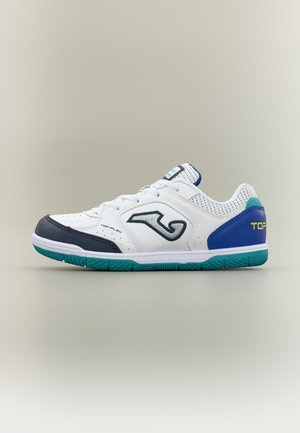 Chaussure de sport basse blanche avec des touches bleu marine et sarcelle, semelle texturée et logo sur le côté et le talon, vue de profil sur un fond neutre.
