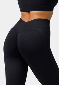 Hoch taillierte schwarze Leggings aus dehnbarem Stoff, mit einer glatten Textur und dezenten Rippdetails entlang des Bundes.