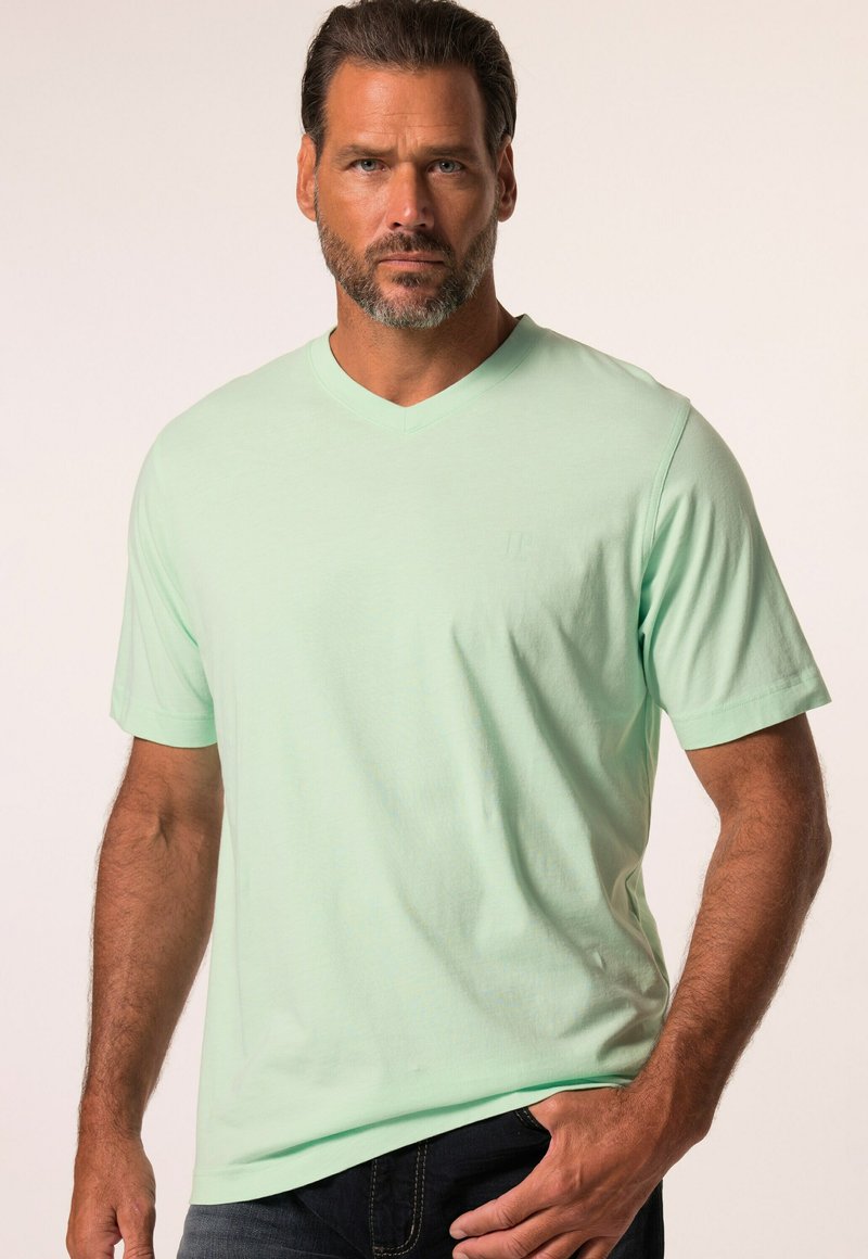 Camiseta verde menta de cuello en V, fabricada con tela suave, presenta mangas cortas y un sutil branding en el pecho. Corte casual y textura suave.