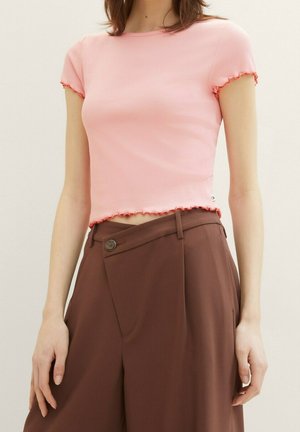 Roze geribbelde crop top met korte, gerimpelde mouwen en een rafelige zoom, gecombineerd met bruine high-waisted broek met een zij-knopdetail.