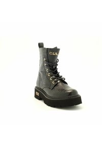 Stivale da combattimento in pelle nera con motivo coccodrillo, occhielli dorati, suola spessa e logo dorato "CULT" sulla linguetta e sul tallone.