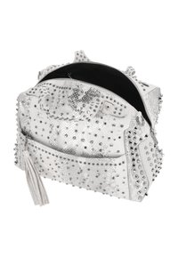 Bolso blanco con tachuelas y textura de piel de serpiente, con tachuelas metálicas y un fleco con borla. Cremallera abierta que revela el interior negro.