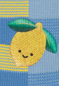 Strickstoff mit gelben Zitronen und grünen Blättern auf einem blau- und gelbgestreiften Hintergrund. Die Zitrone hat ein lächelndes Gesicht.