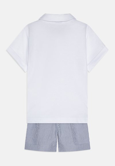 Weißes Polohemd mit Kragen und kurze Ärmel, kombiniert mit blau-weiß gestreiften Shorts, die eine lockere Passform und weichen Stoff aufweisen.