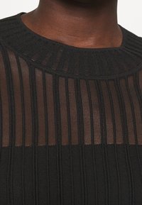 Top nero a coste caratterizzato da strisce orizzontali trasparenti e un collo rotondo testurizzato, che mette in mostra una finitura liscia e un design leggermente stratificato.