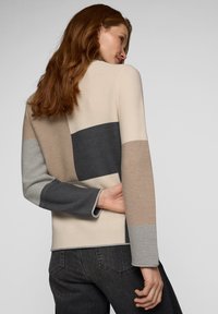 Strickpullover mit einem Farbblockdesign in Beige, Grau und dunklen Farbtönen. Lange Ärmel mit einer subtilen Textur und Rundhalsausschnitt.