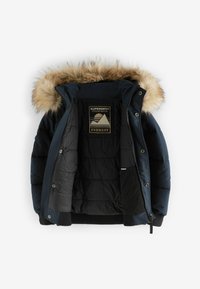 Mornarski pufasti kaput s umjetnim krznom na kapuljači. Ima kviltanu teksturu, prednji rajsferšlus i unutarnju oznaku koja glasi "Superdry Expedition Co. Everest."