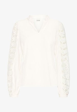 Weiße Bluse mit V-Ausschnitt, strukturiertem Stoff und langen Ärmeln, die an den äußeren Seiten mit aufwendiger Spitzenverzierung versehen sind.