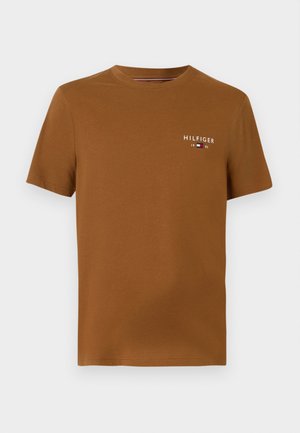 T-shirt en coton marron avec col rond et manches courtes. Présente un petit logo blanc "HILFIGER" et l'année "1985" sur la poitrine.