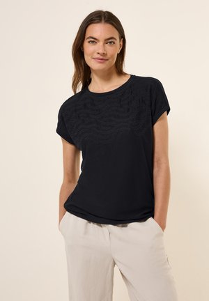 T-shirt noir à manches courtes avec un motif texturé en vagues sur le devant, col rond et coupe décontractée. Le tissu semble doux et léger.