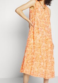 Ærmeløs, lagdelt kjole i orange med lyserøde abstrakte mønstre, lavet af letvægtsstof, med sidelommer og en afslappet pasform.