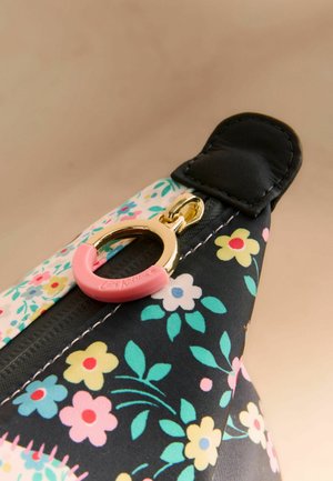 Cremallera con anilla dorada y pestaña rosa en tela con estampado floral que presenta flores en tonos pastel amarillo, rosa, azul y verde.