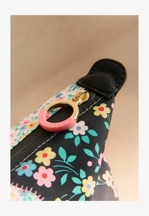 Cremallera con anilla dorada y pestaña rosa en tela con estampado floral que presenta flores en tonos pastel amarillo, rosa, azul y verde.